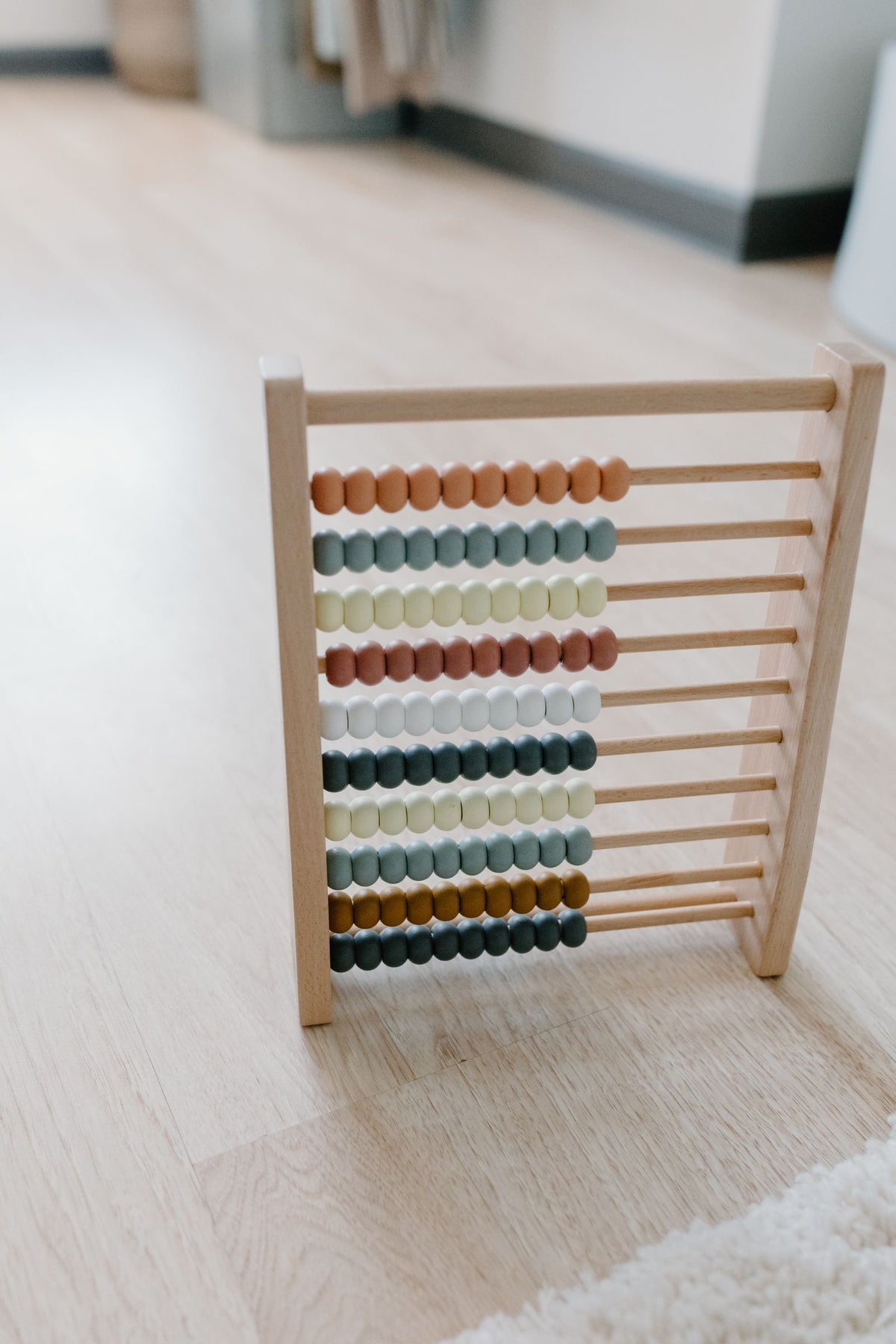 Abaque en bois aux perles colorées posé sur un parquet clair